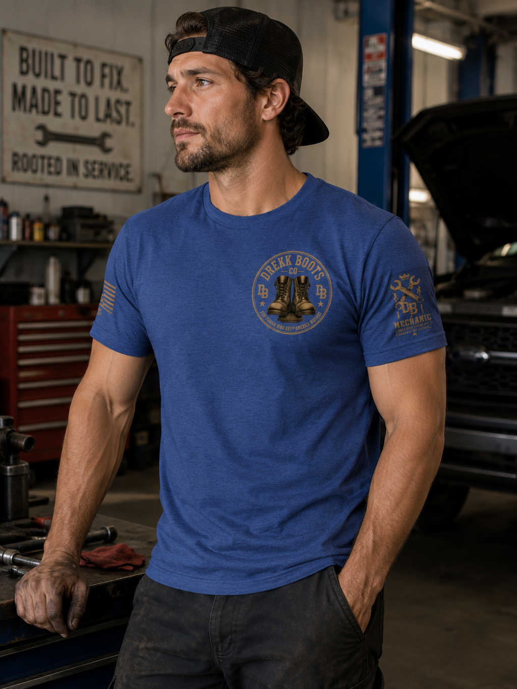 Mechanic Vintage Graphic T-Shirt in blue with circular boots logo by DREKK Boots Co., worn in a workshop.